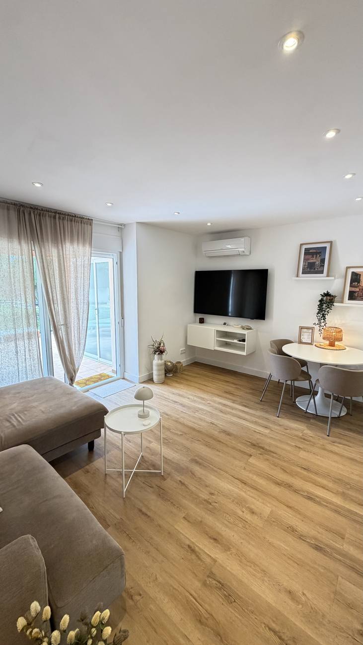Wohnzimmer mit Ecksofa, Fernseher und Essplatz